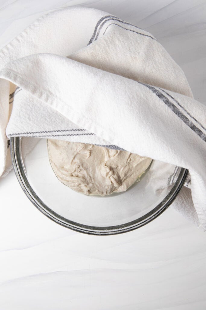 Proof the gluten free sourdough pizza dough in a bowl with a thin towel over it.