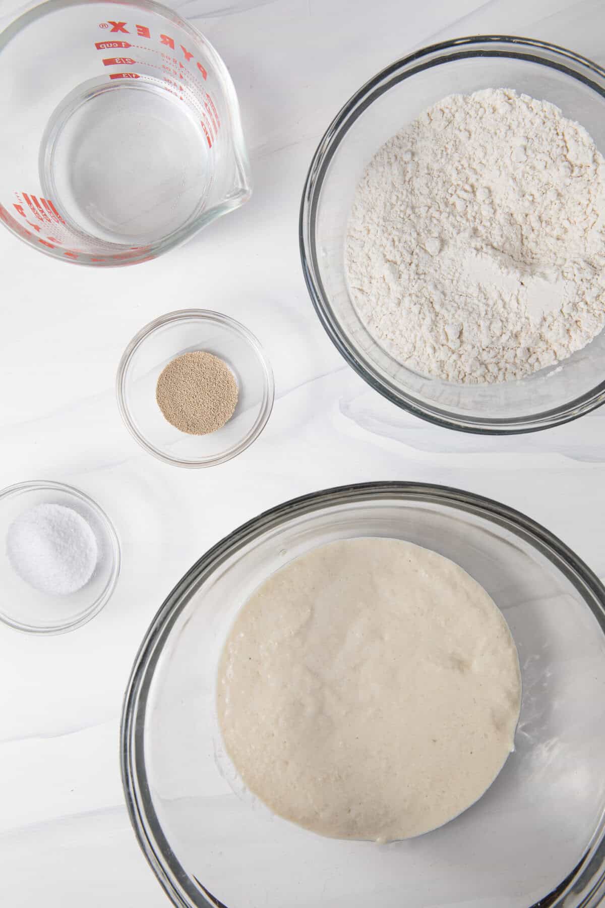 ingredients for the gluten free sourdough pizza crust that are pre-measured in bowls.