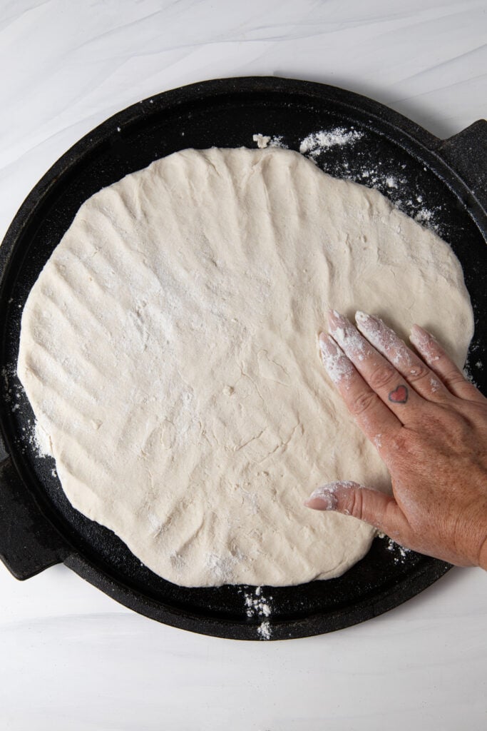 Pat the gluten free sourdough pizza dough on a cast iron thin.