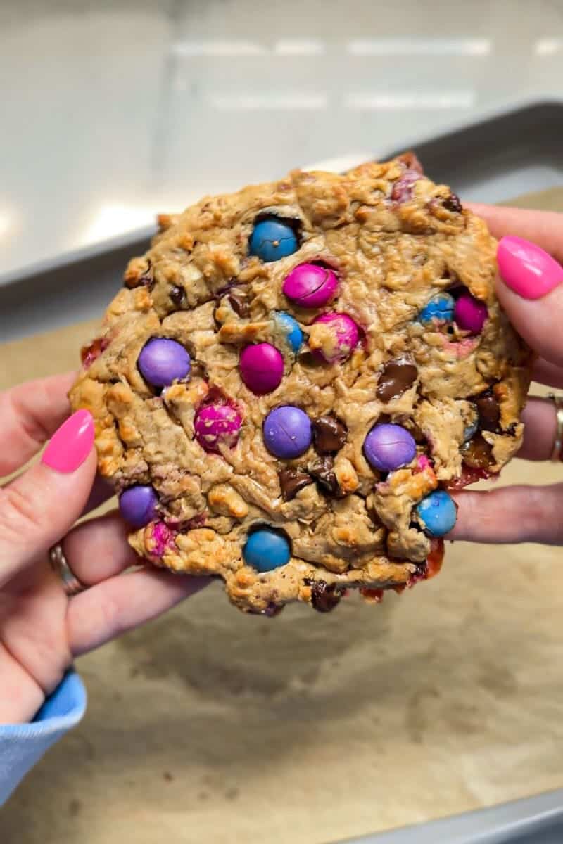 hands holding an oatmeal chocolate chip protein cookie