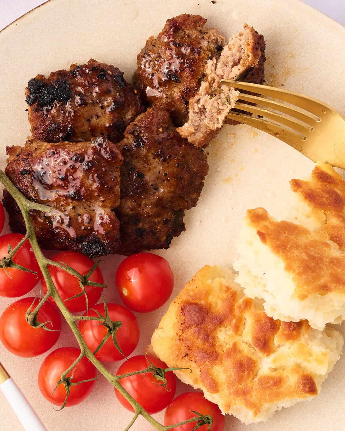 turkey breakfast sausage patties on a plate with tomato and biscuits