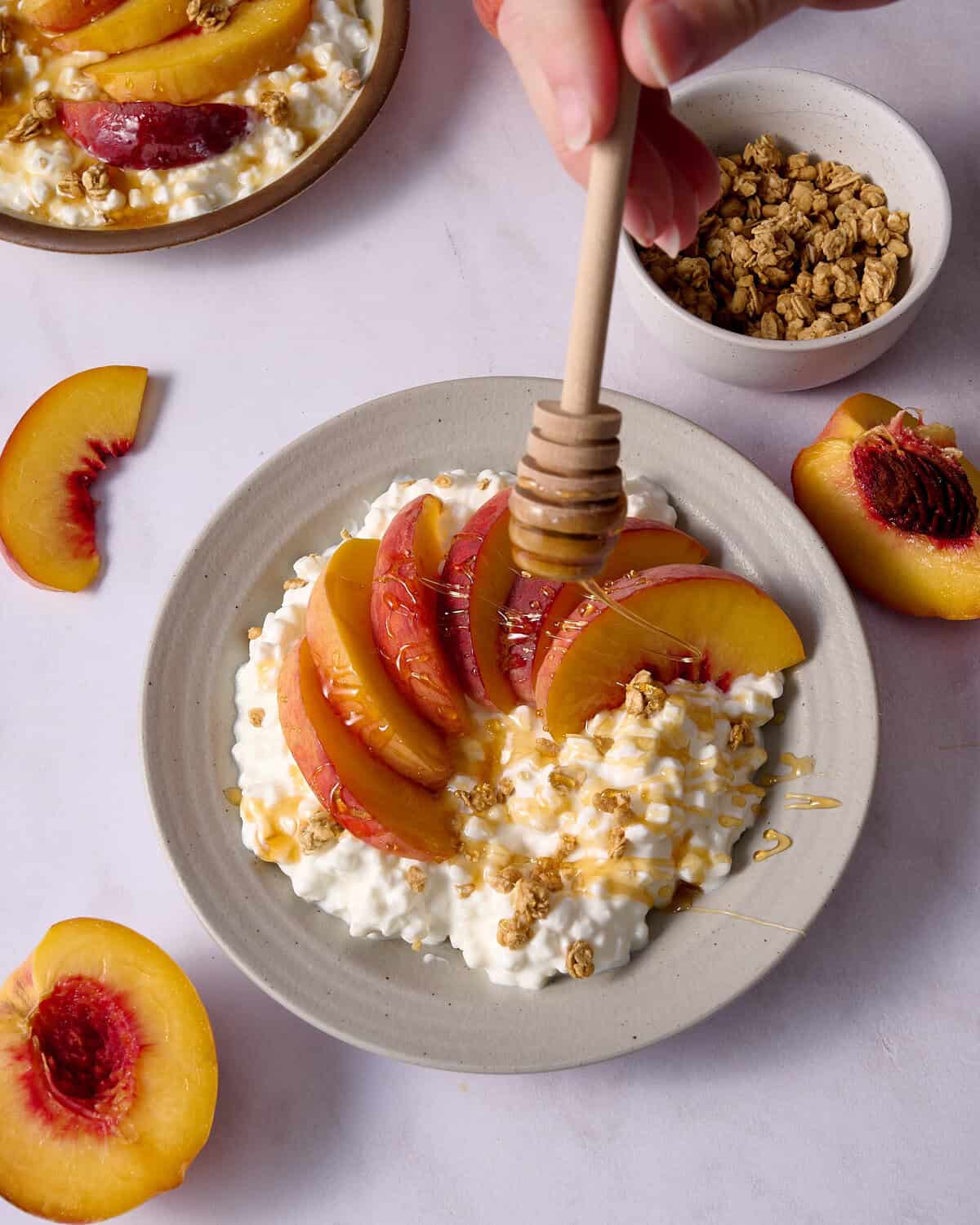 drizzling honey over bowls of cottage cheese and peaches