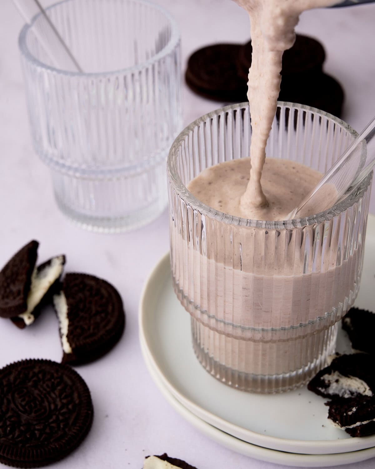 pouring cookies & cream protein shake into a glass