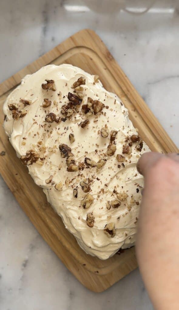 Garnish the top of the cream cheese frosting with walnuts and shredded carrot for the high protein carrot cake.