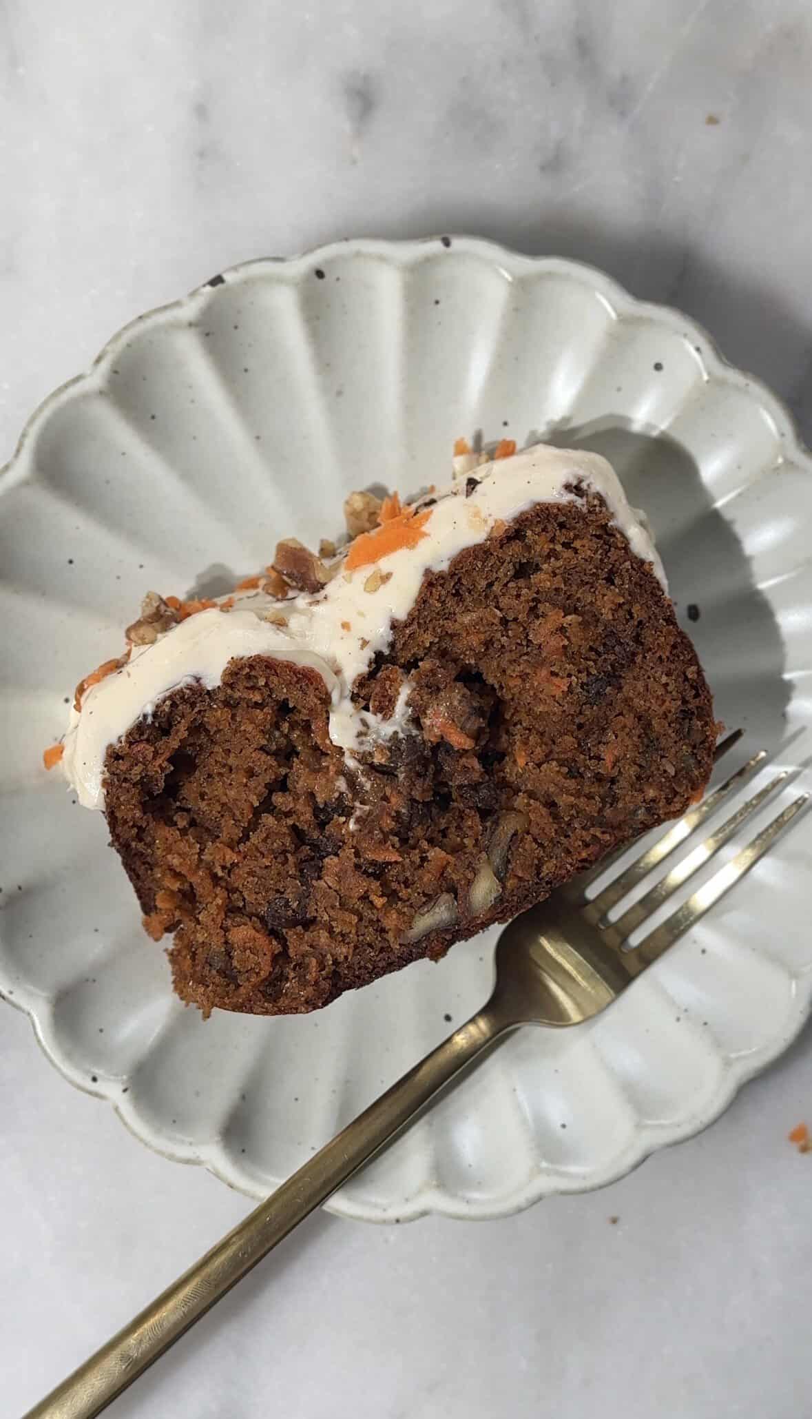 Close up of the baked and frosted Easy High Protein Carrot Cake slice on a plate with a fork for serving.