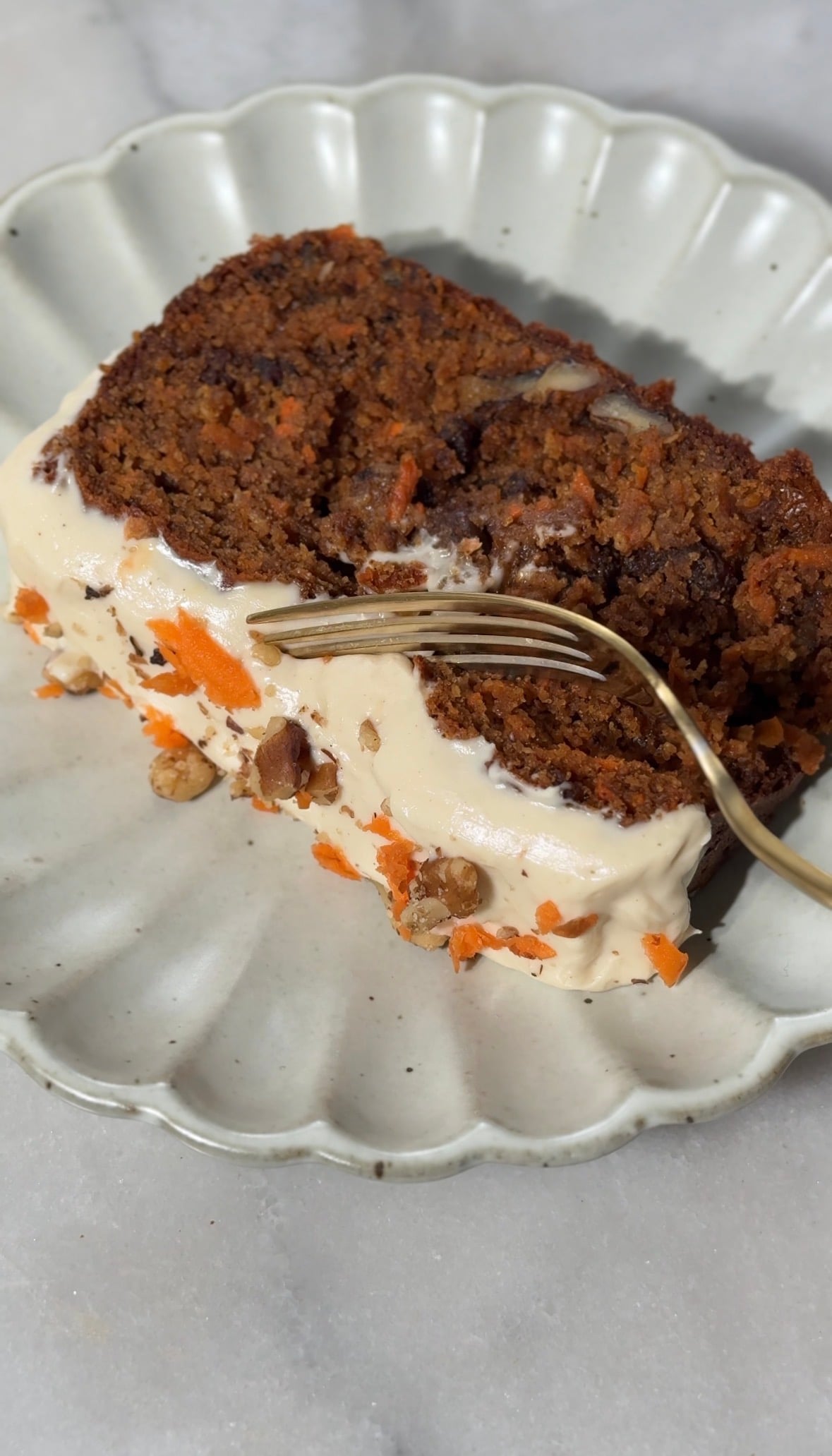 Close up of the baked and frosted Easy High Protein Carrot Cake on a plate being enjoyed with a fork.