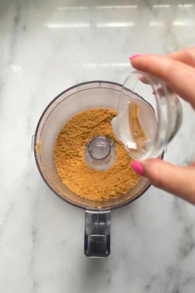 Pour coconut oil into the graham cracker crumbs in the food processor for the crust of the No Bake Lemon Cottage Cheese Cheesecake Cups.