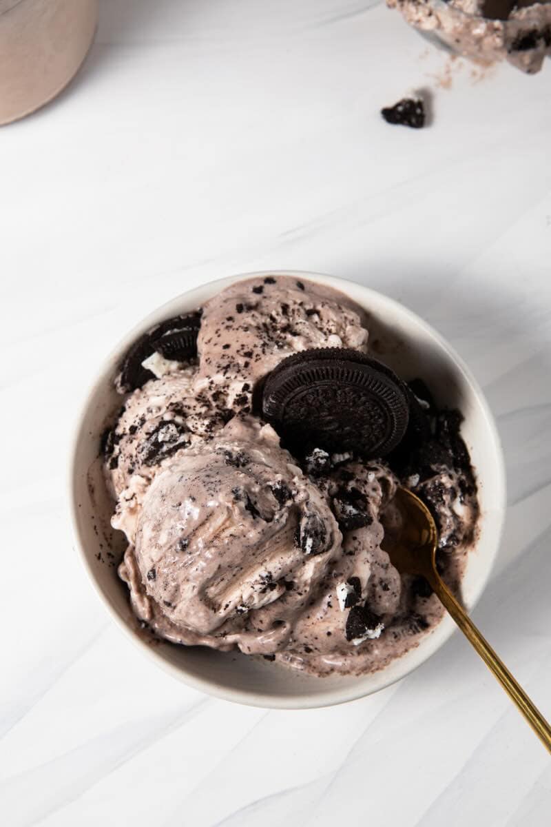 Completed Ninja Creami Protein Dairy Free Oreo Cookies and Cream Ice Cream in a bowl with crushed up gluten free Oreos being served with a spoon.