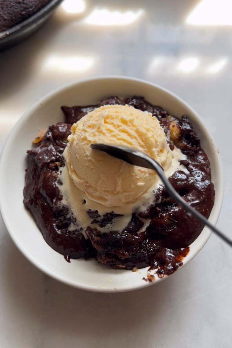 protein skillet brownie in a bowl with ice cream on top.