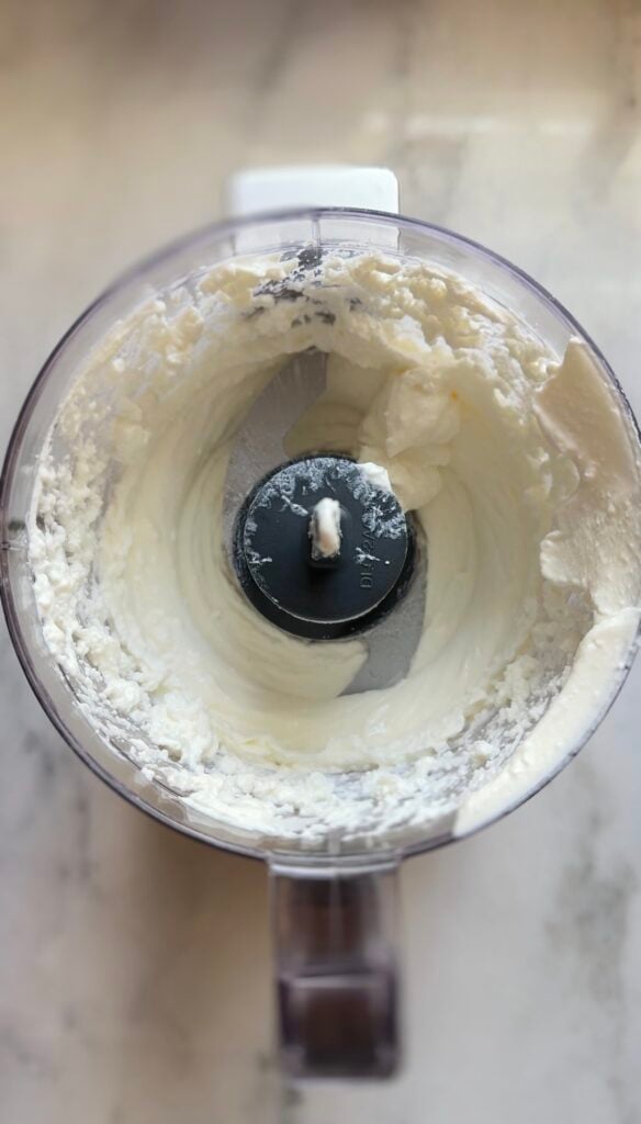 Blending high fat cottage cheese in a food processor until completely smooth for the blueberry protein muffins.