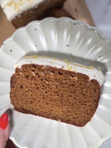 Finished slice of protein lemon cake with protein cream cheese frosting on a plate.