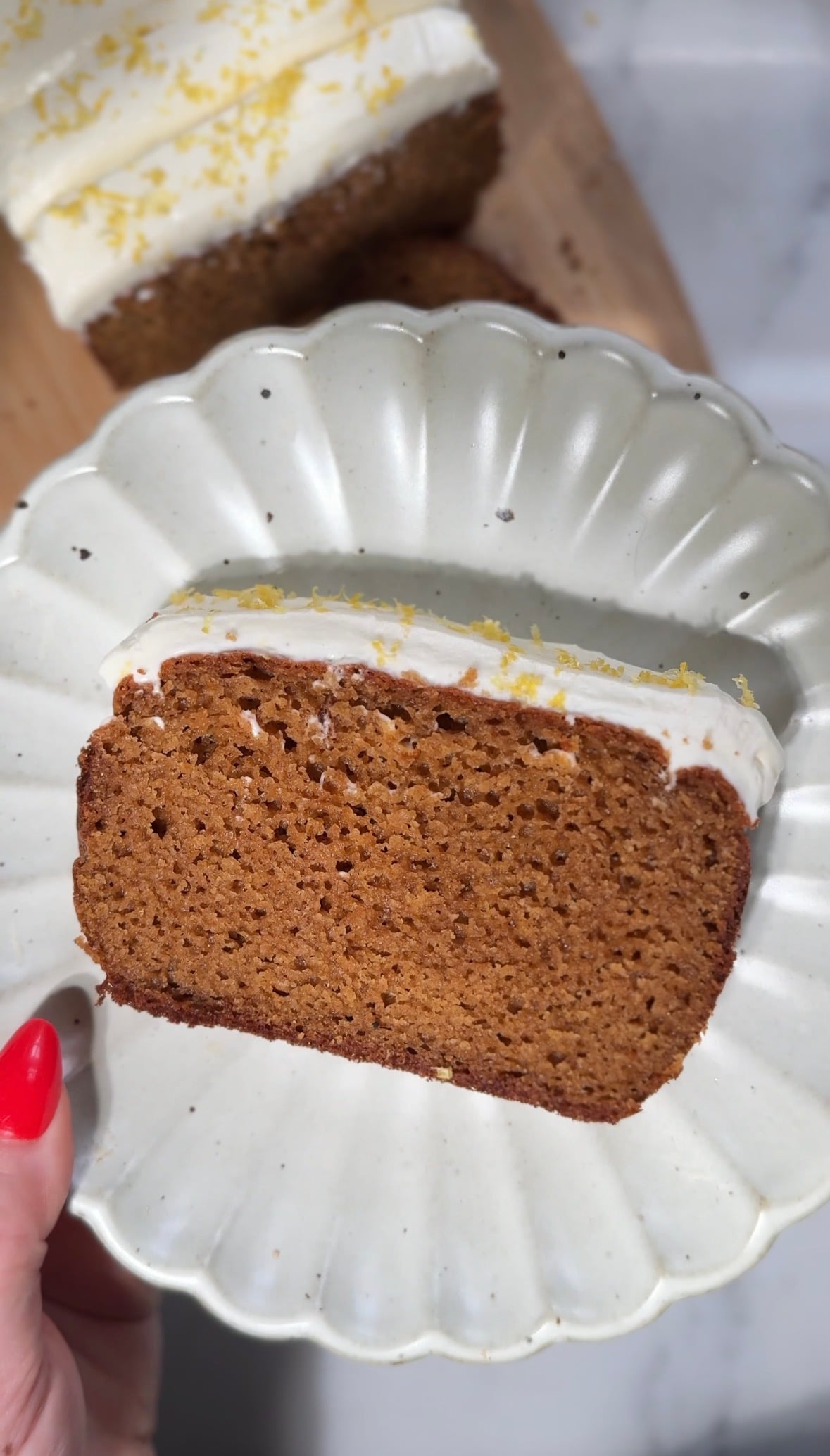 Finished slice of protein lemon cake with protein cream cheese frosting on a plate.