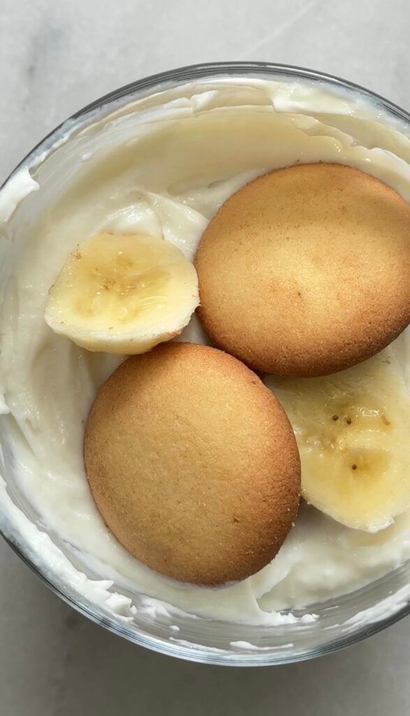 Layer the easy protein banana pudding base with the first layer of banana and gluten-free vanilla wafers in a bowl or glass.