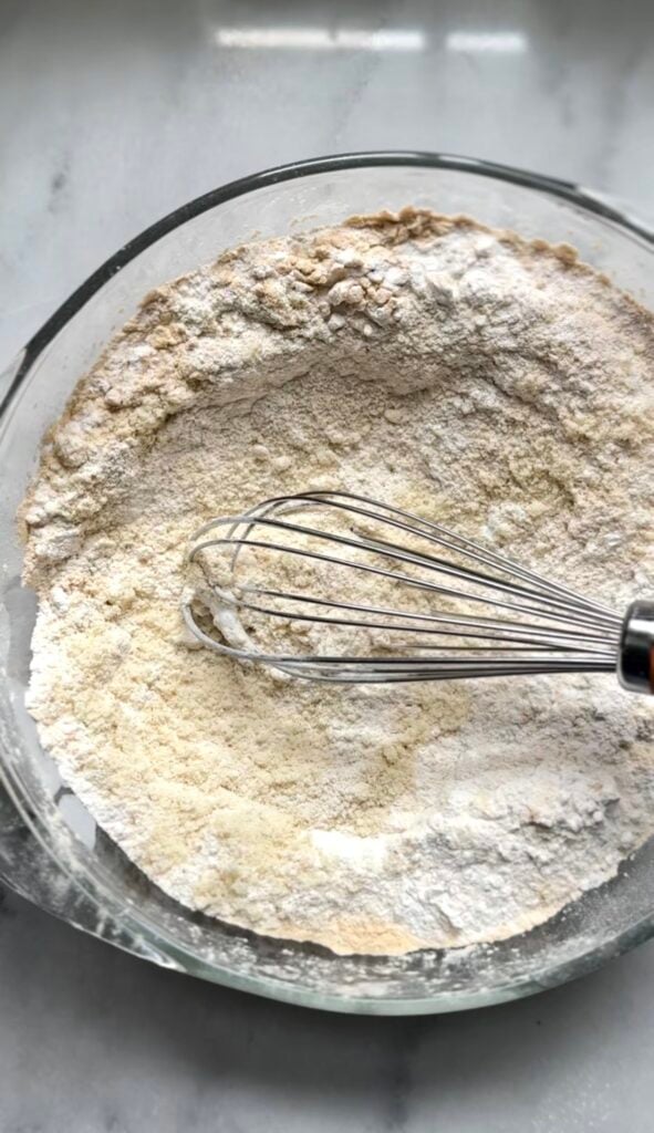 All the dry ingredients for the protein lemon cake mixed together by whisk in a bowl.