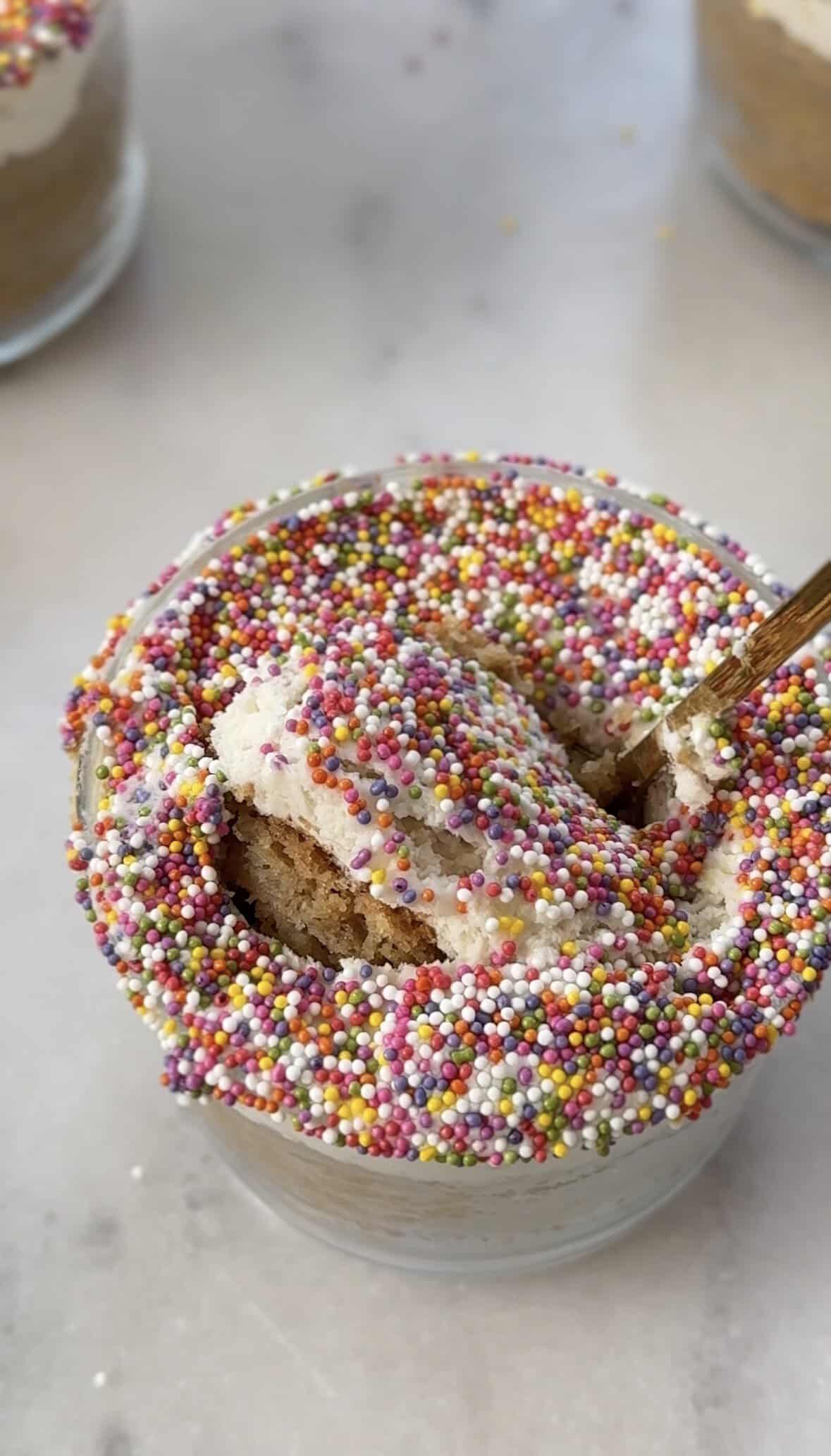 Close up of my dairy free and gluten free version of the viral dot cake recipe in a glass with a piece of cake getting scooped with a spoon.