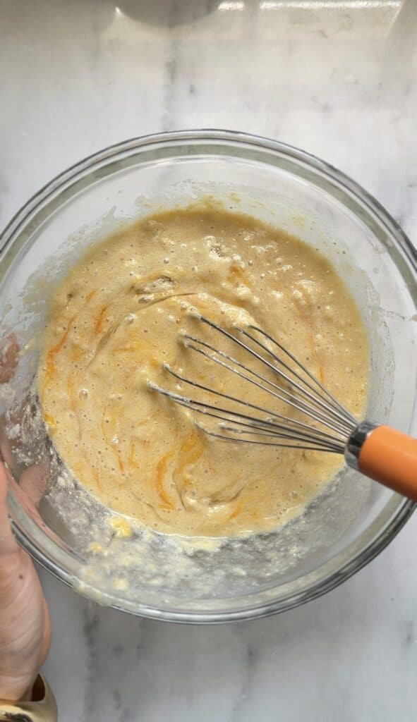 Mixing the dairy free and gluten free viral dot cake recipe a bowl with a whisk.