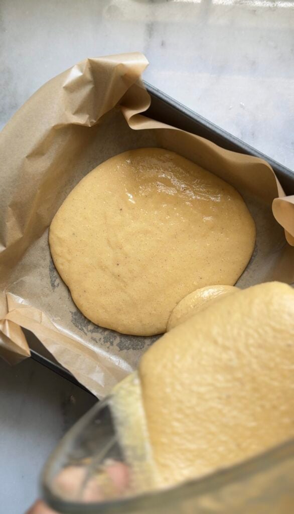 Pour the dairy free and gluten free viral dot cake recipe in the 8x8 cake pan lined with parchment paper.