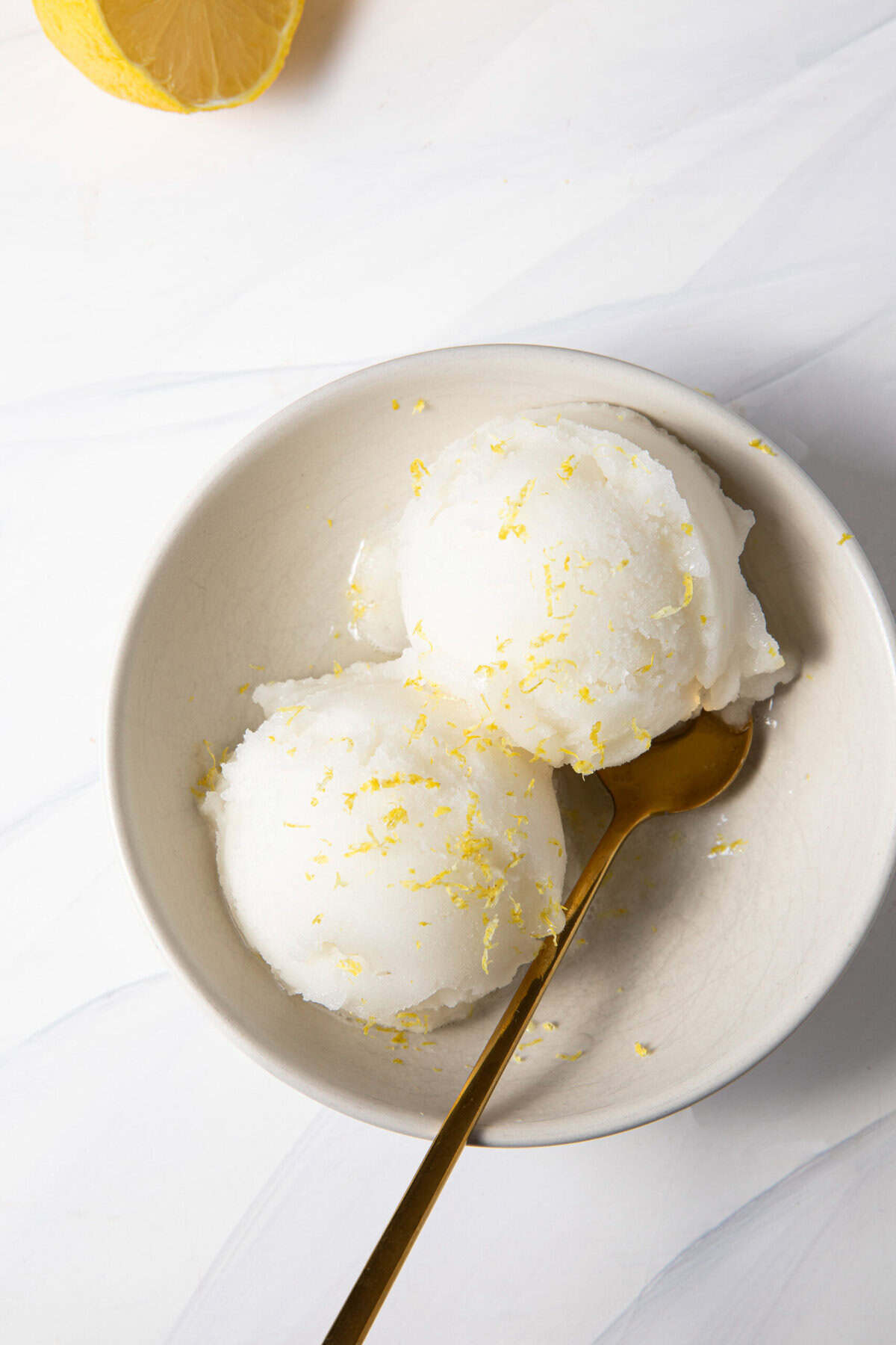 Ninja Creami Lemon Sorbet in a bowl with a spoon topped with lemon zest.
