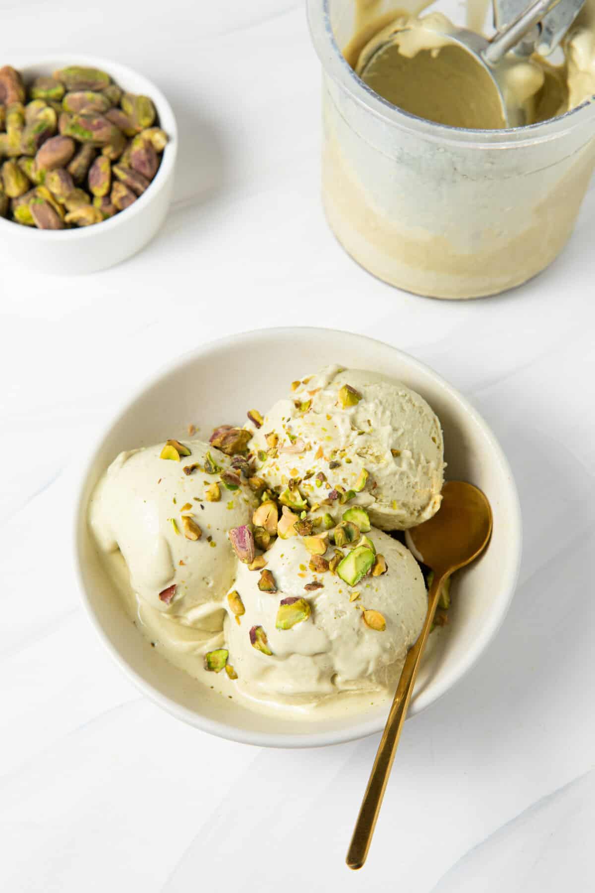 Pistachio ice cream scooped into a bowl topped and served with a spoon.