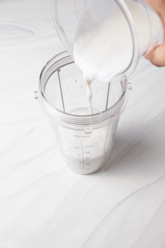 Pour almond milk into the blender bottle.