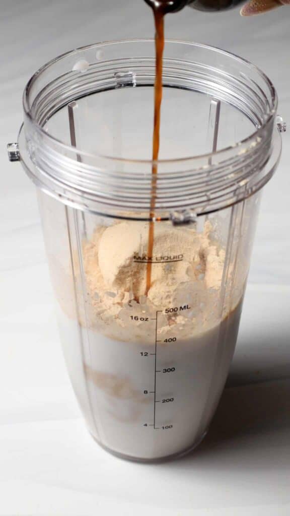 Pour the vanilla extract into the blender bottle for the Birthday Cake Batter Protein Ninja Creami Ice Cream base.
