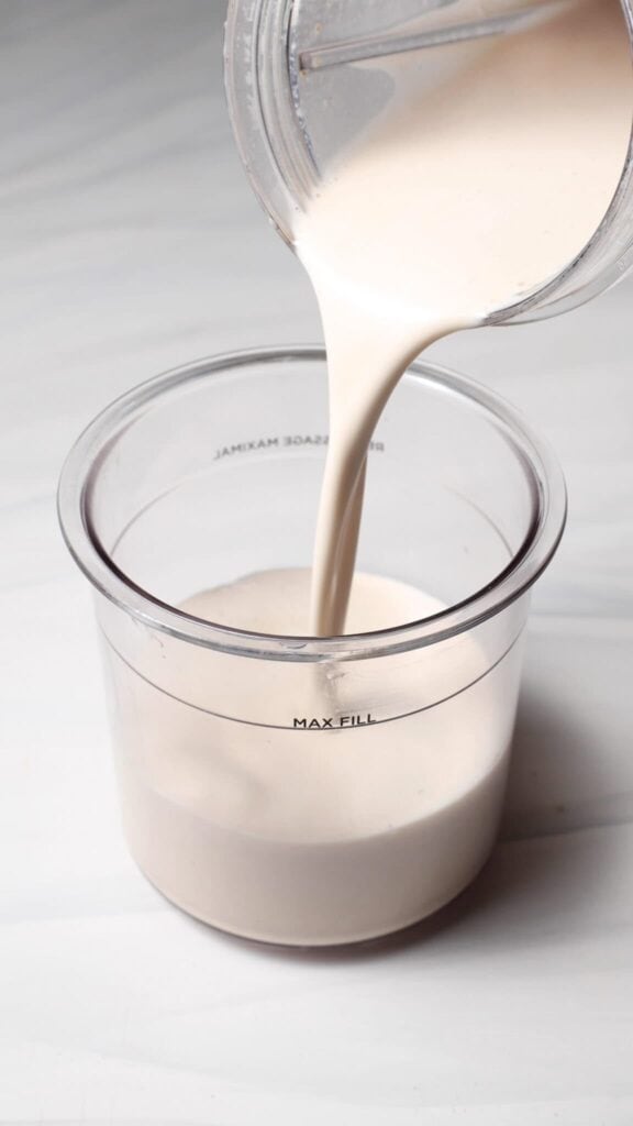 Pour the Birthday Cake Batter Protein Ninja Creami Ice Cream base from the blender bottle in the Ninja Creami pint.