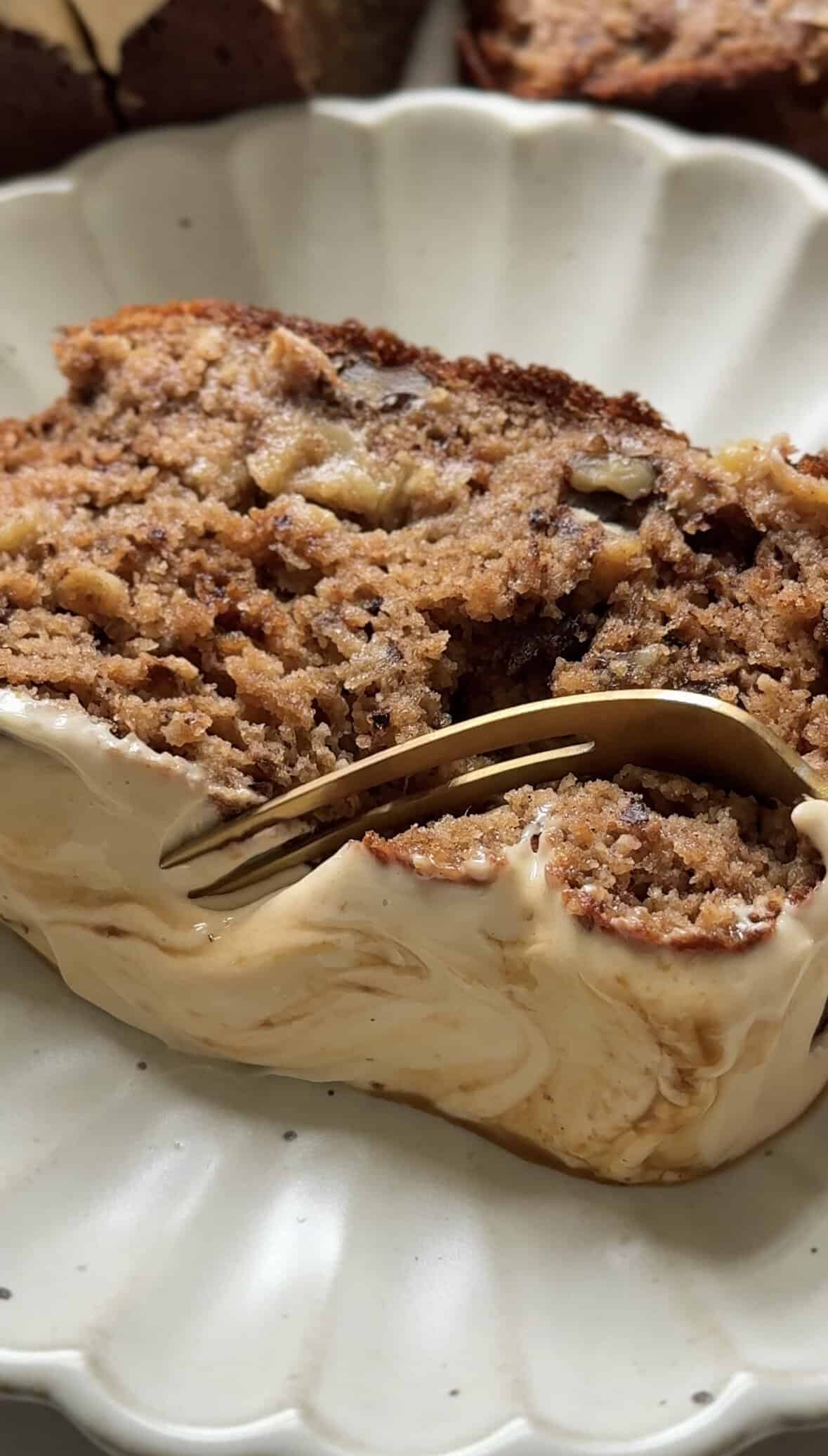A bite being taken out of the Gluten Free Protein Banana Nut Bread on a plate with a fork.