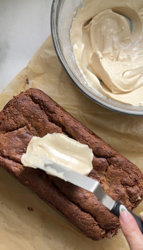 Frosting the Gluten Free Protein Banana Nut Bread with the cream cheese frosting.