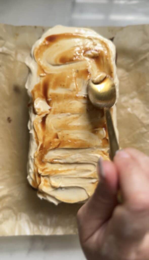 Spreading out the caramel banana syrup on top of the cream cheese frosting for the gluten free banana nut bread.