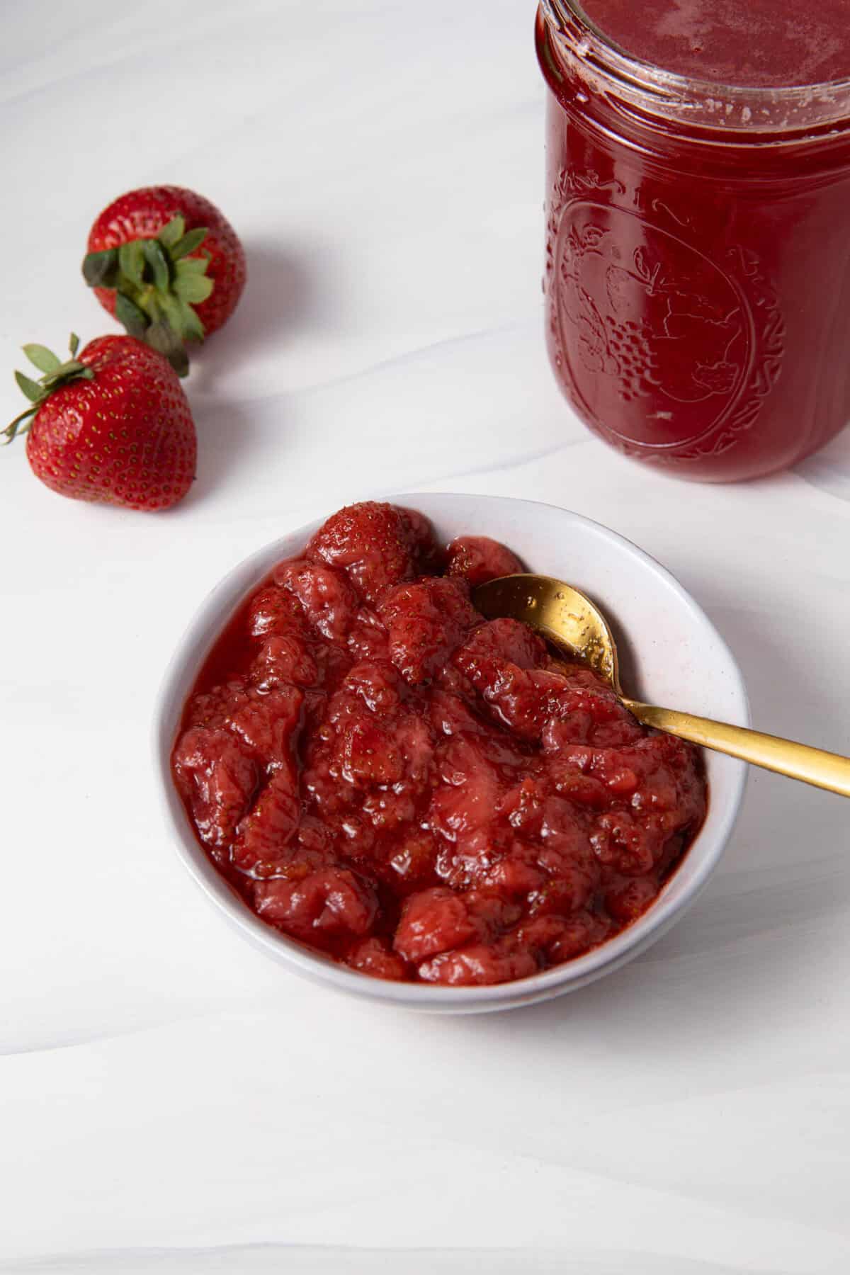 Spoon the Fresh Strawberry Simple Syrup compote from a bowl with a spoon.