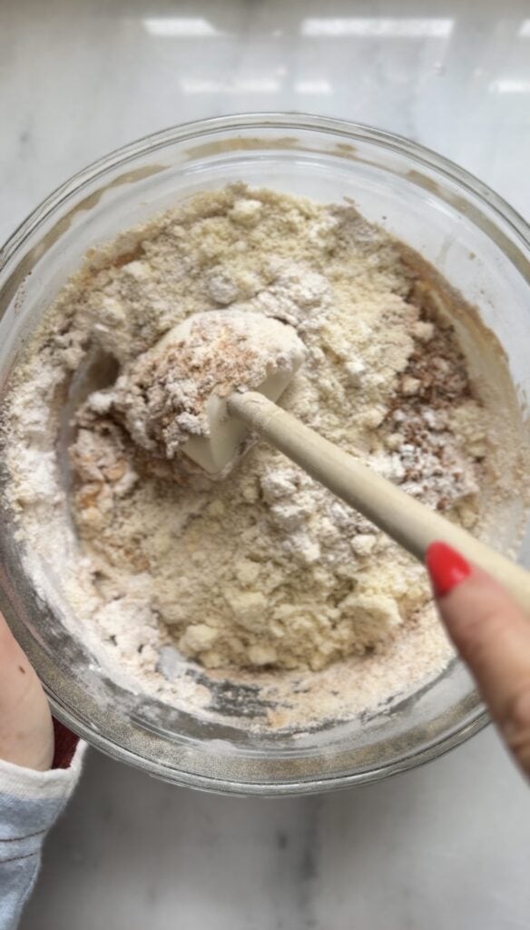 Begin to fold in the dry and wet ingredients for the Gluten Free Protein Pumpkin Bread in a bowl with a rubber spatula.