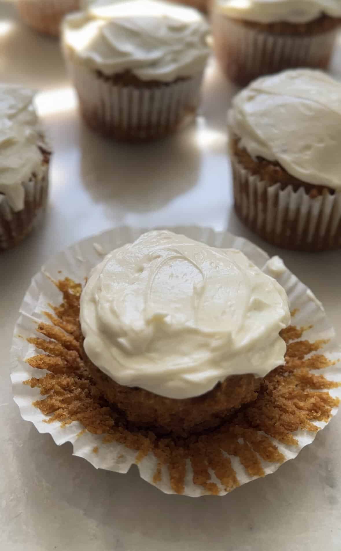 Pumpkin cottage cheese muffins with cream cheese frosting in the muffin liner.