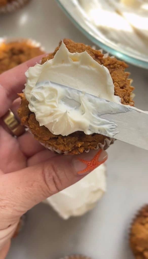 Spread the cream cheese frosting on top of the pumpkin cottage cheese muffins with a butter knife.
