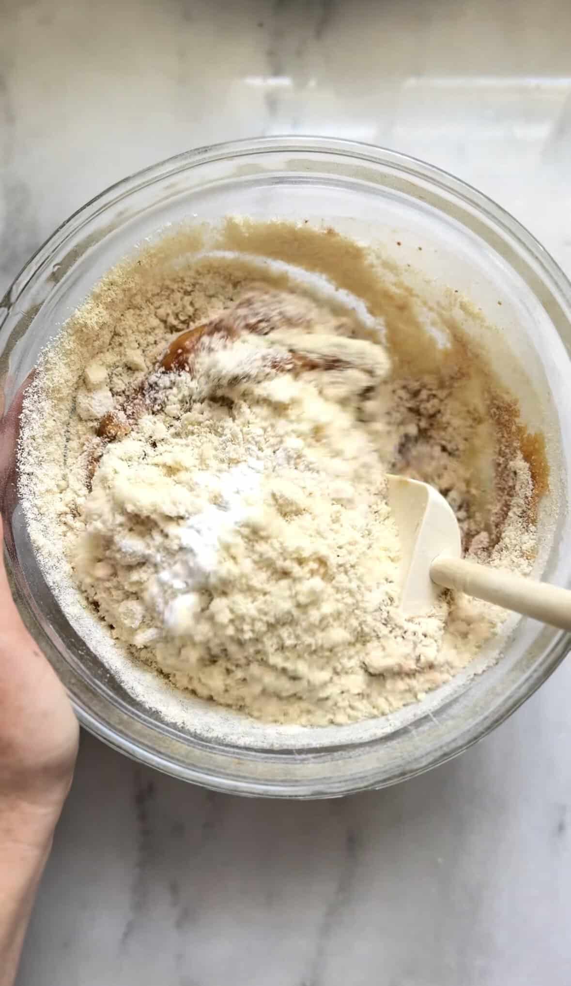 Fold the dry ingredients of the banana donuts into the same bowl as the wet ingredients.