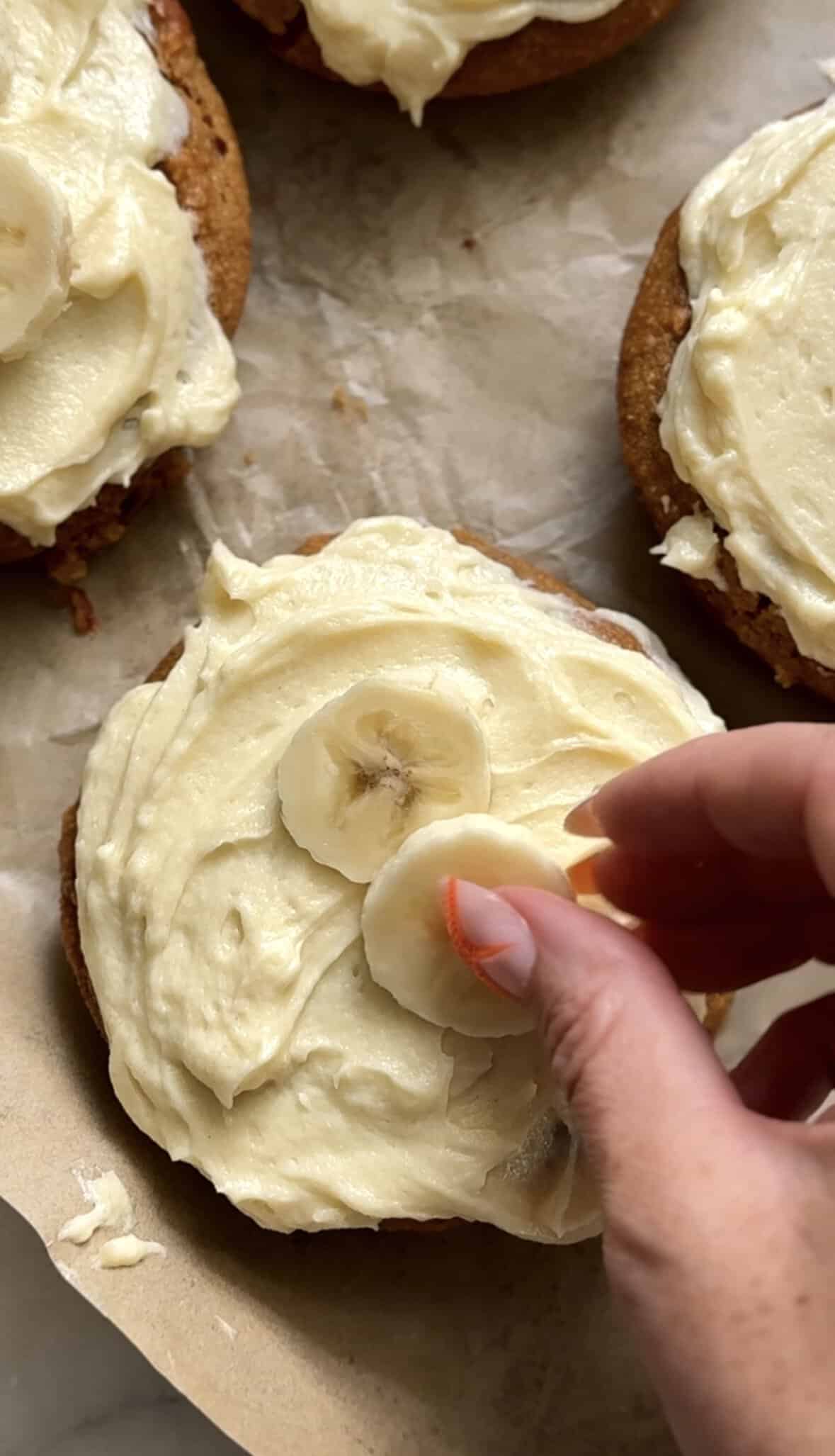 Top each frosted banana donut with fresh sliced banana slices.