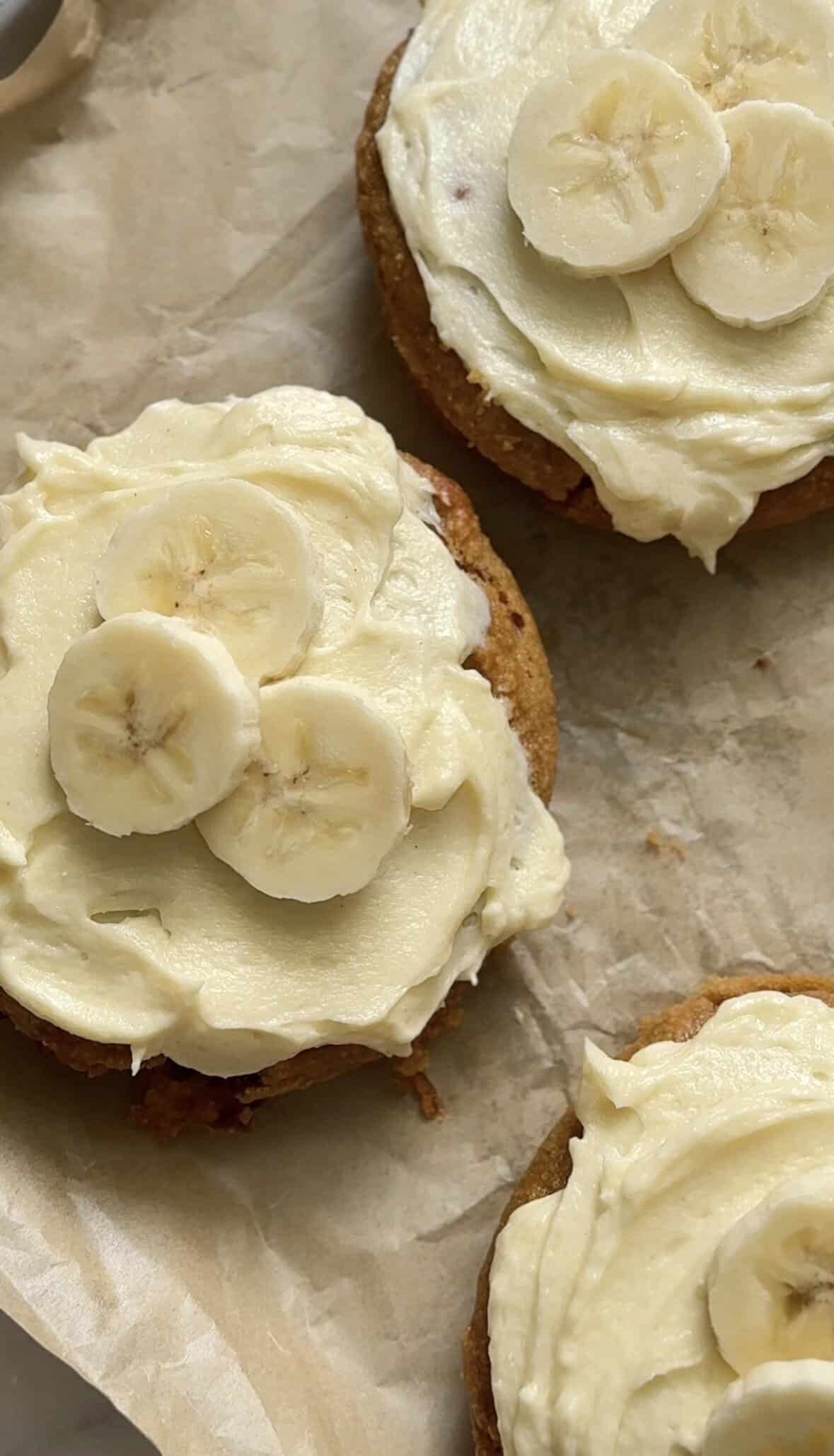 Close of the Gluten Free Baked Banana Donuts topped with fresh sliced bananas on a sheet pan ready to be eaten.