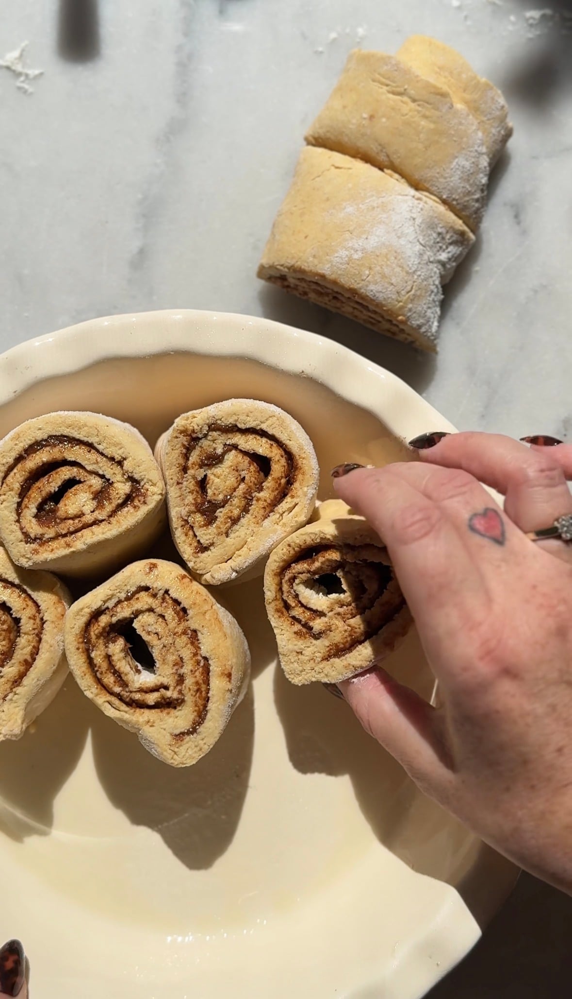 Begin to arrange the cinnamon rolls into a greased baking dish.
