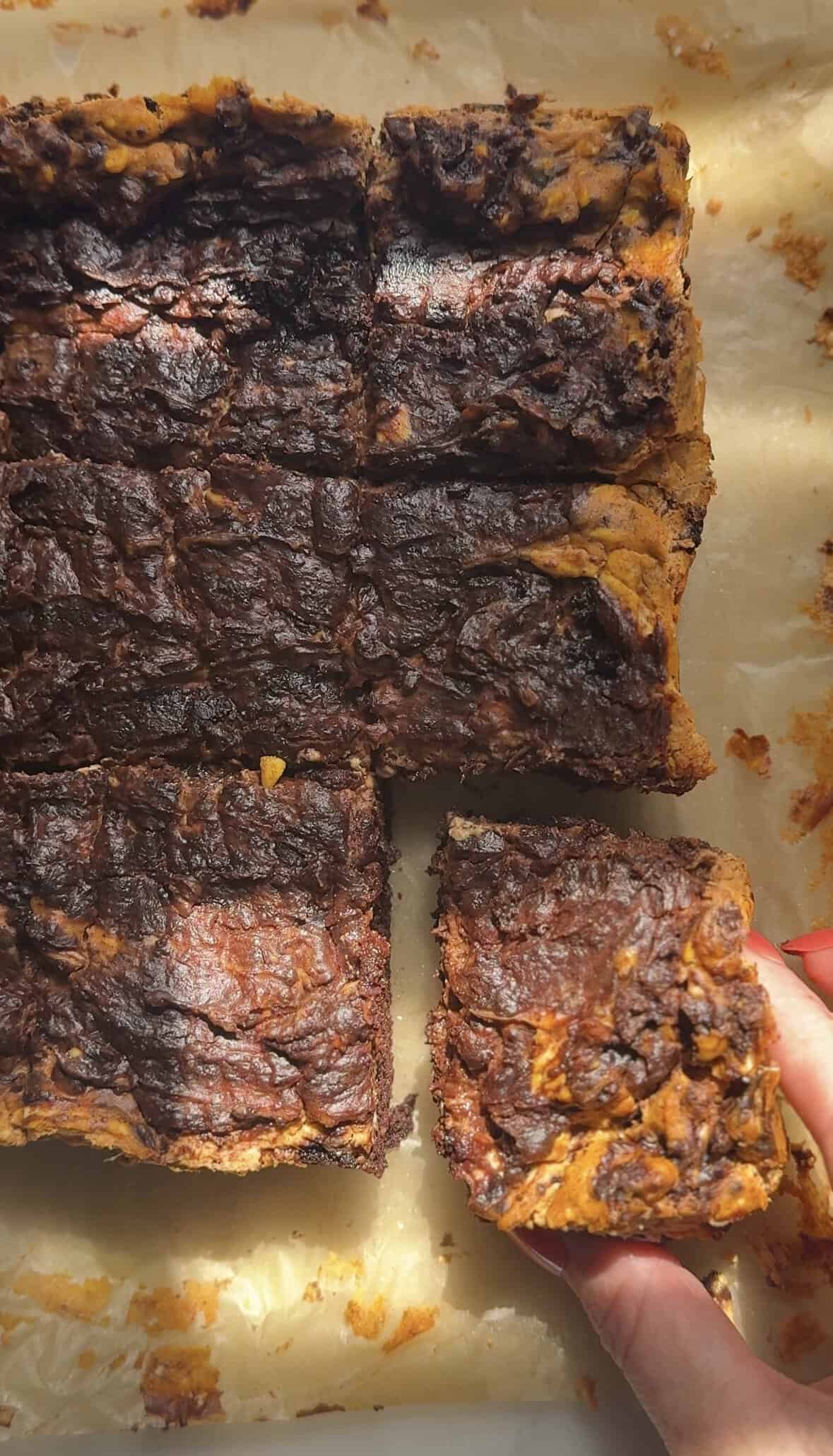 Cut out piece of the Pumpkin Brownie from the whole pan of Pumpkin Brownies on parchment paper.