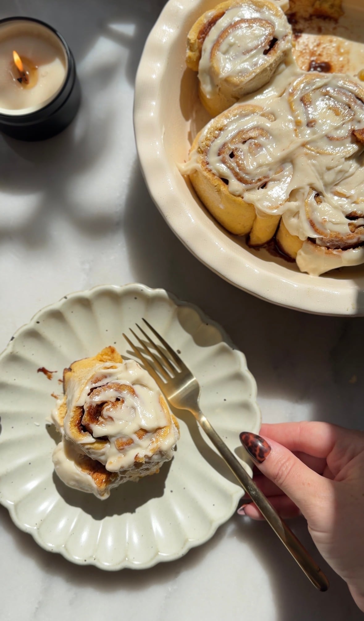 Glazed pumpkin cottage cheese cinnamon roll on a plate and baking dish.