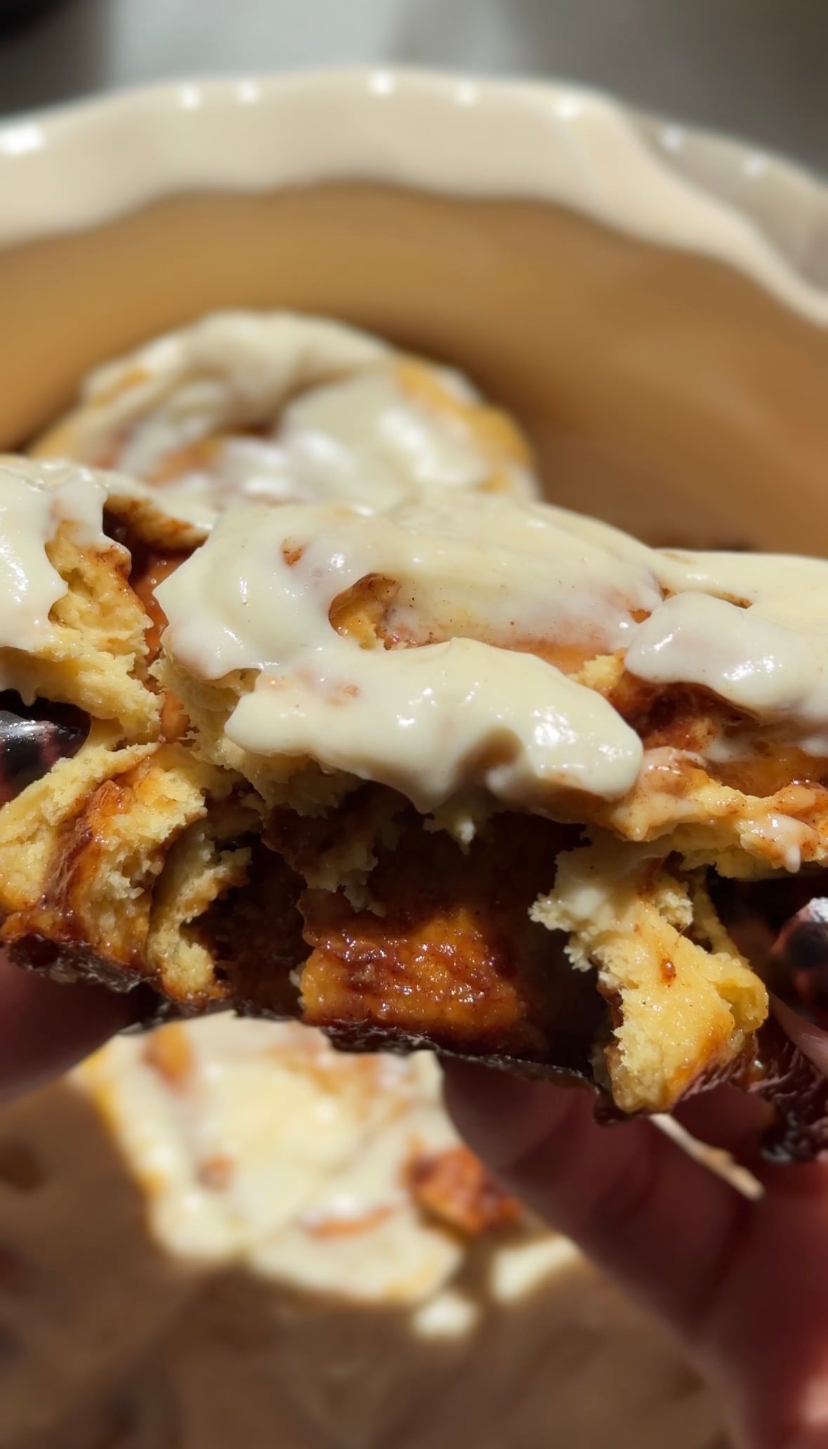 Close up of the glazed pumpkin cottage cheese cinnamon roll being torn apart to show the soft texture of the dough and the gooey filling.