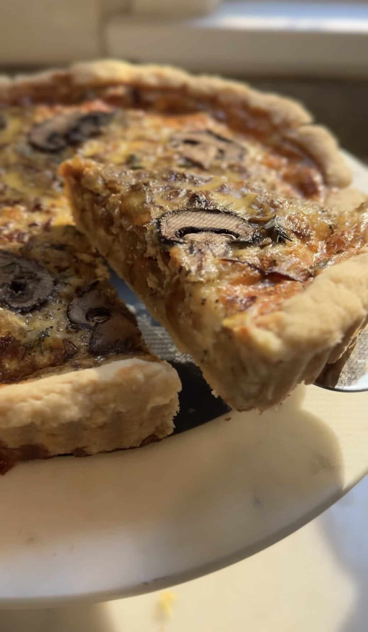 Close up on a slice being taken out of a baked Gluten Free Caramelized Onion Quiche.