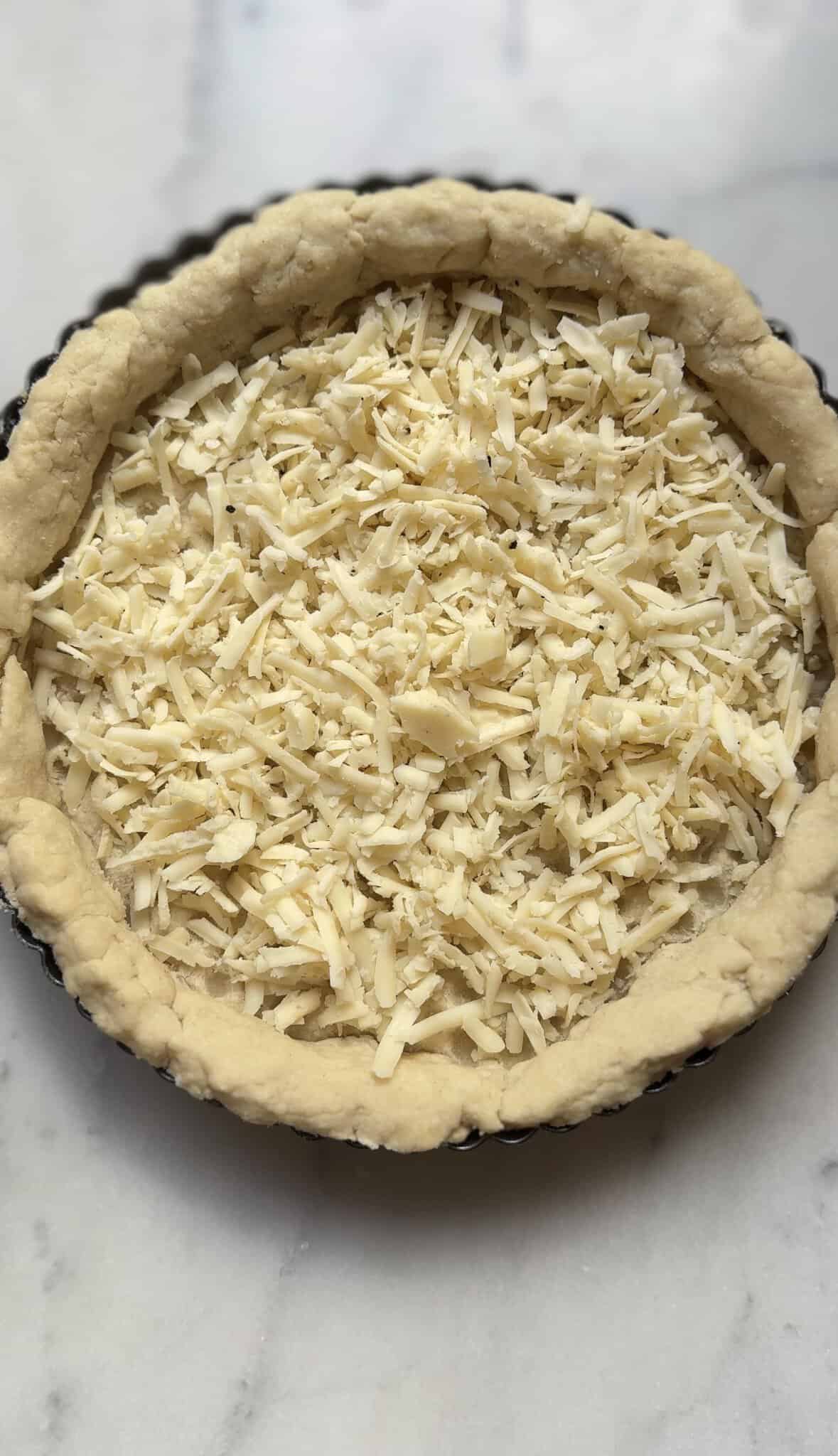 Add shredded cheese to the bottom of a par-baked pie crust.
