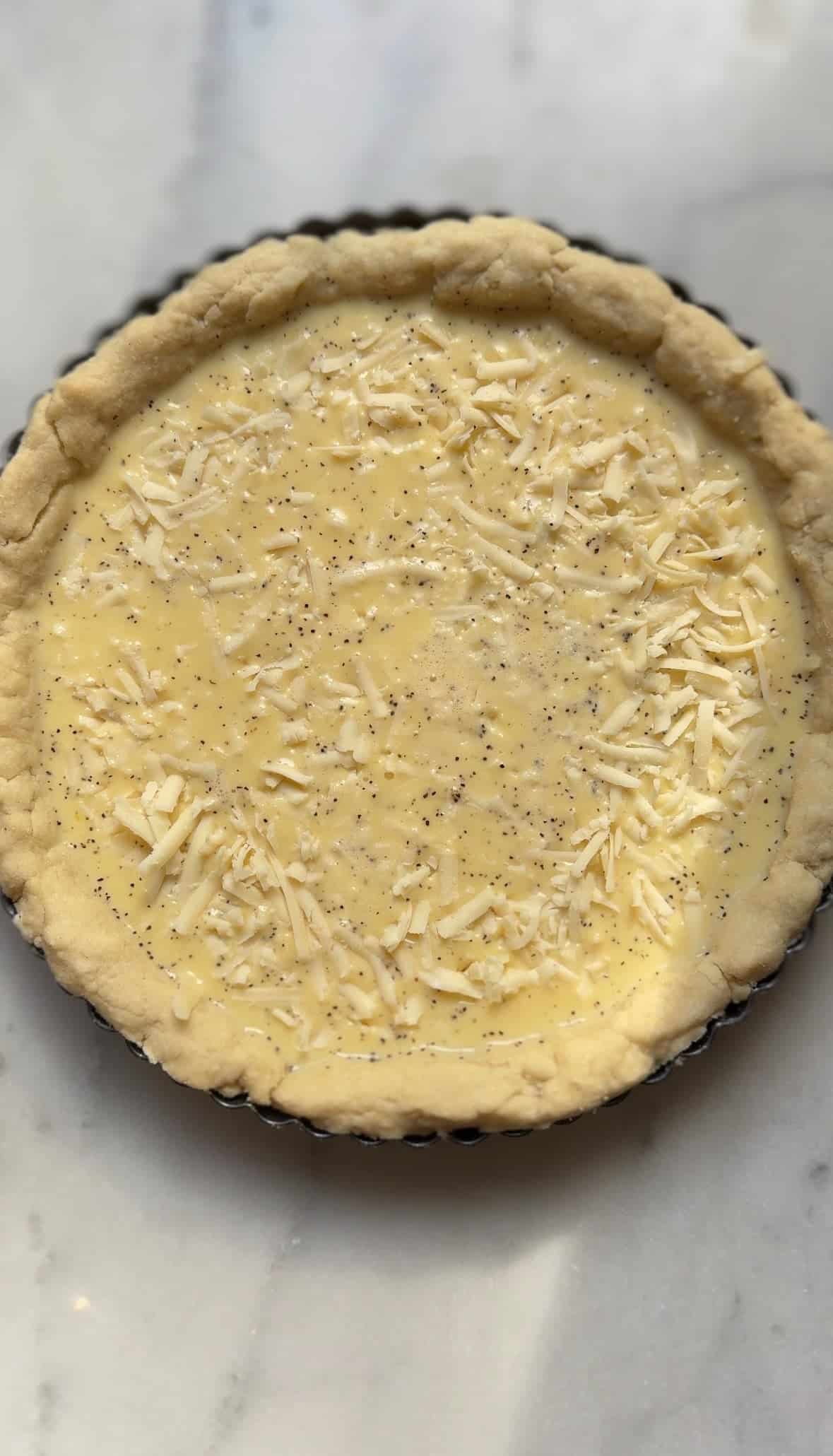 Pour the egg custard over the shredded cheese in the par-baked pie crust.