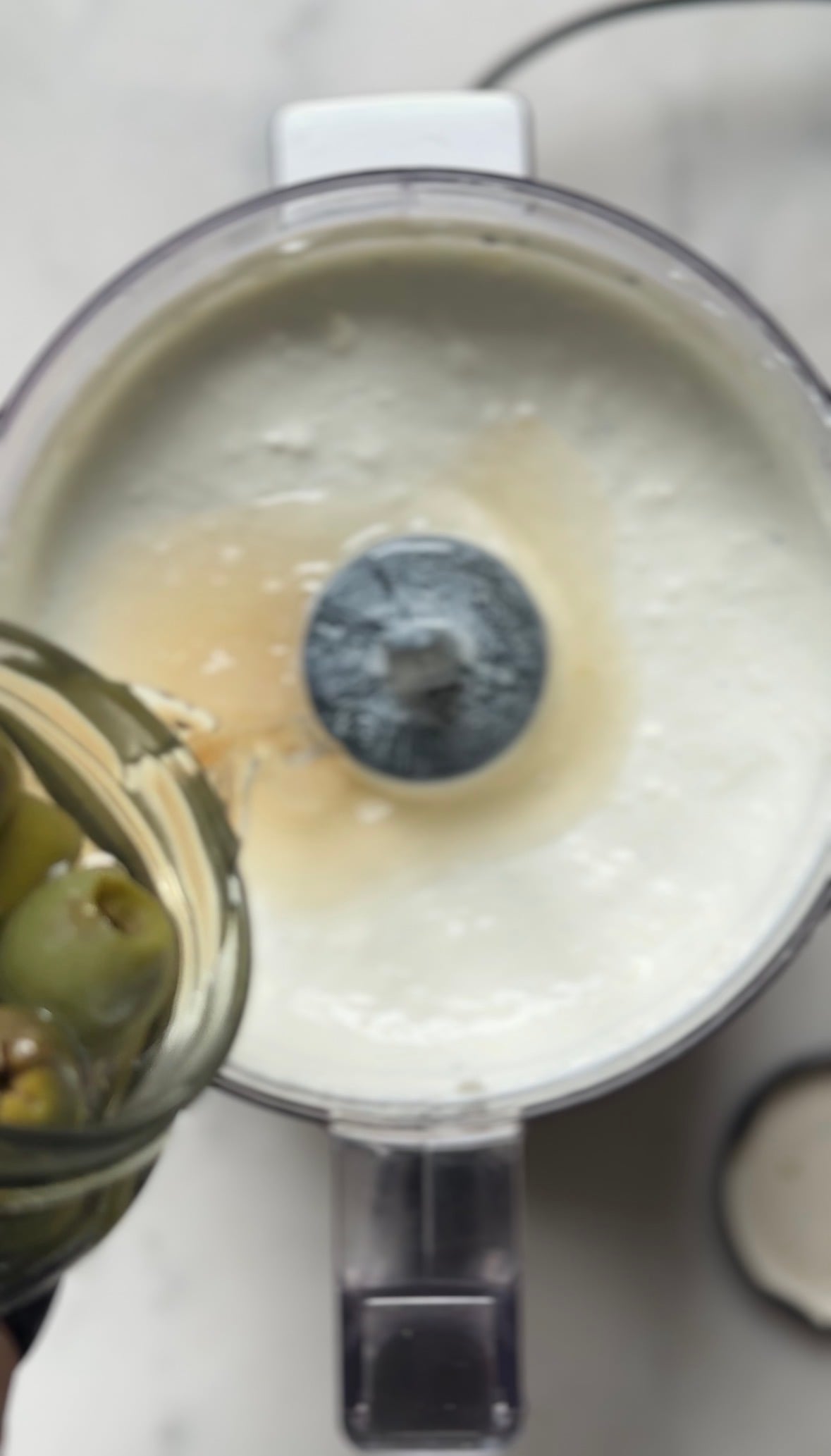 Add the olive brine into the food processor with the blended dirty martini dip base.