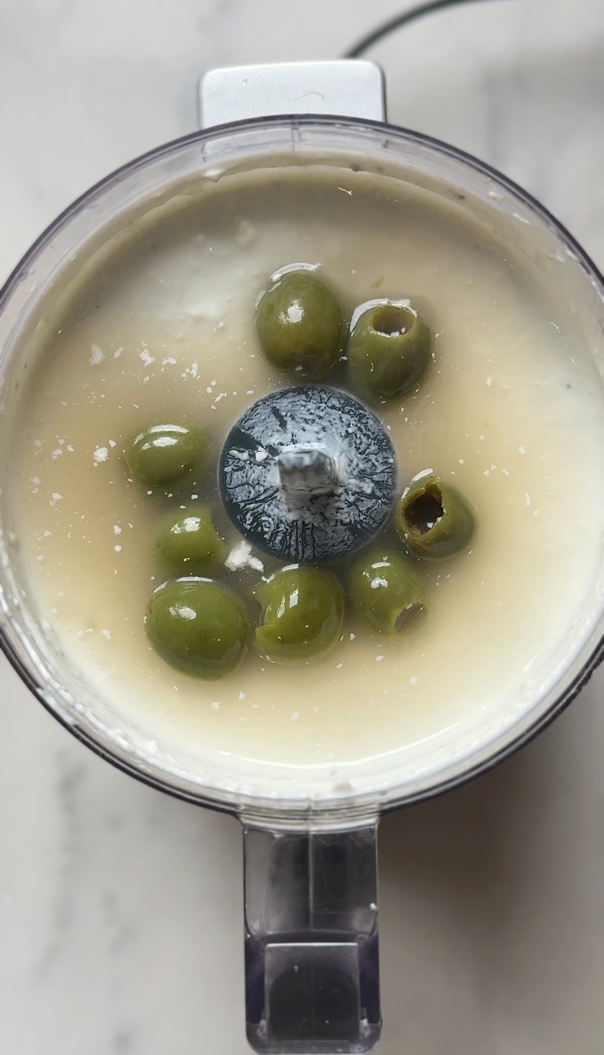Add the olives into the food processor with the blended dirty martini dip base.