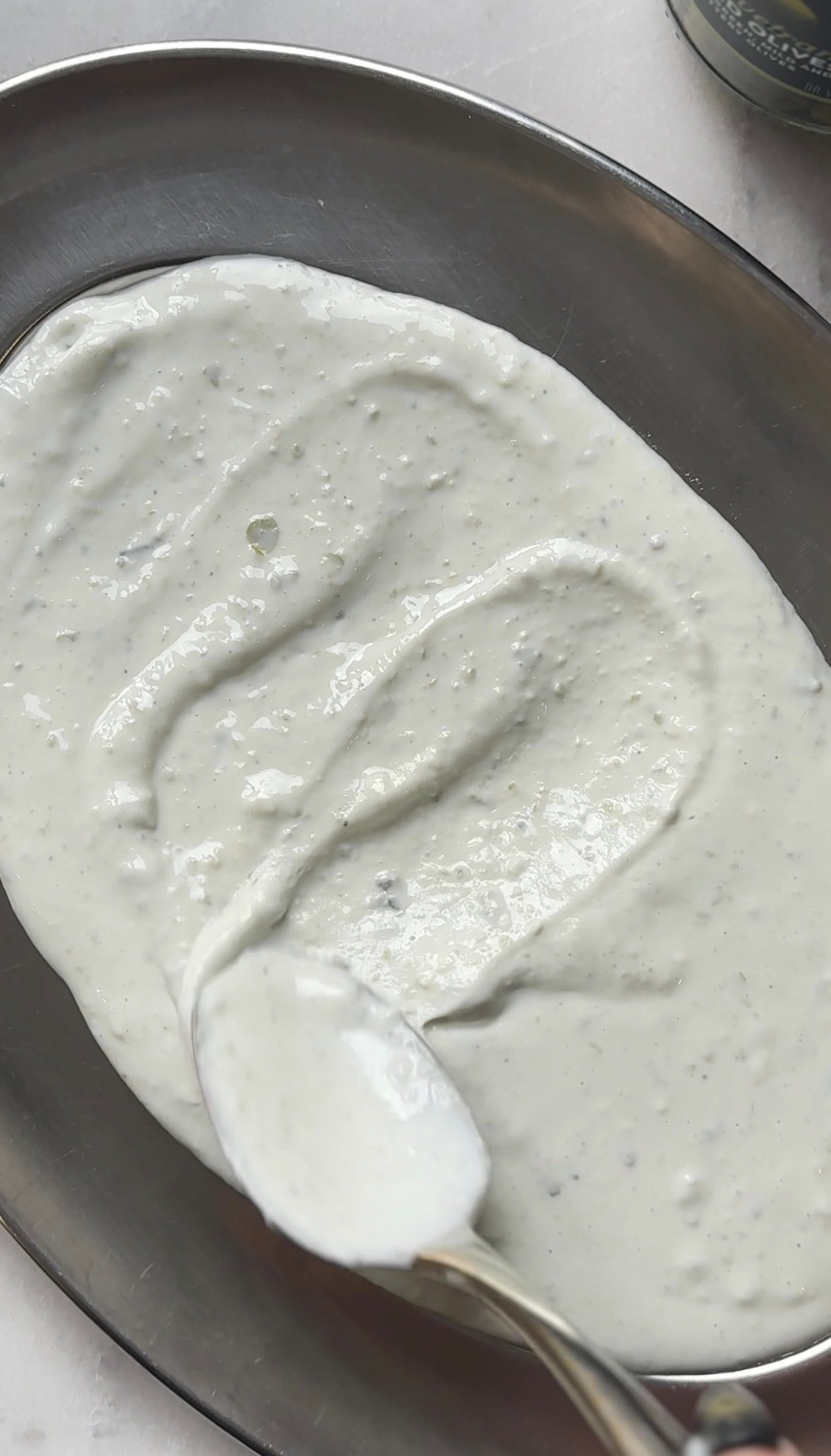 Spread the protein dirty martini dip in the serving bowl or plate of choice.