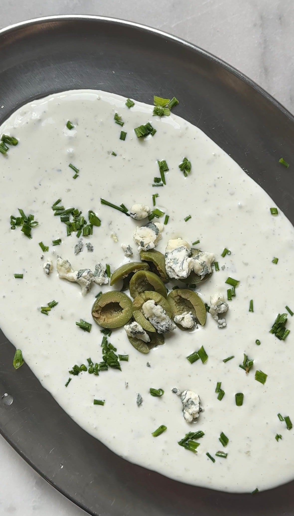 Top the protein dirty martini dip with chives, olives, and more blue cheese.