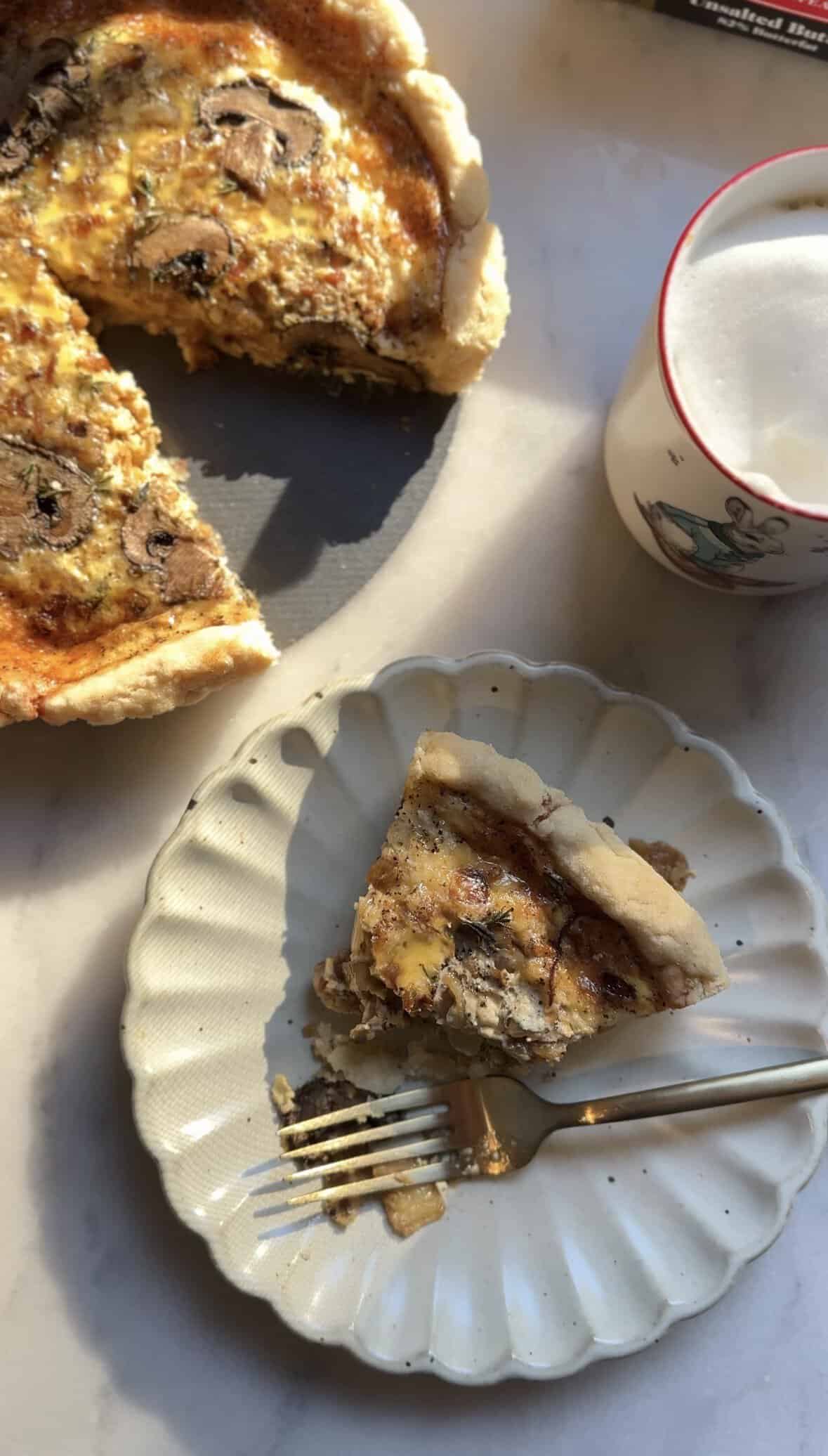 A slice of the Gluten Free Caramelized Onion Quiche on a plate with a bite out of it.