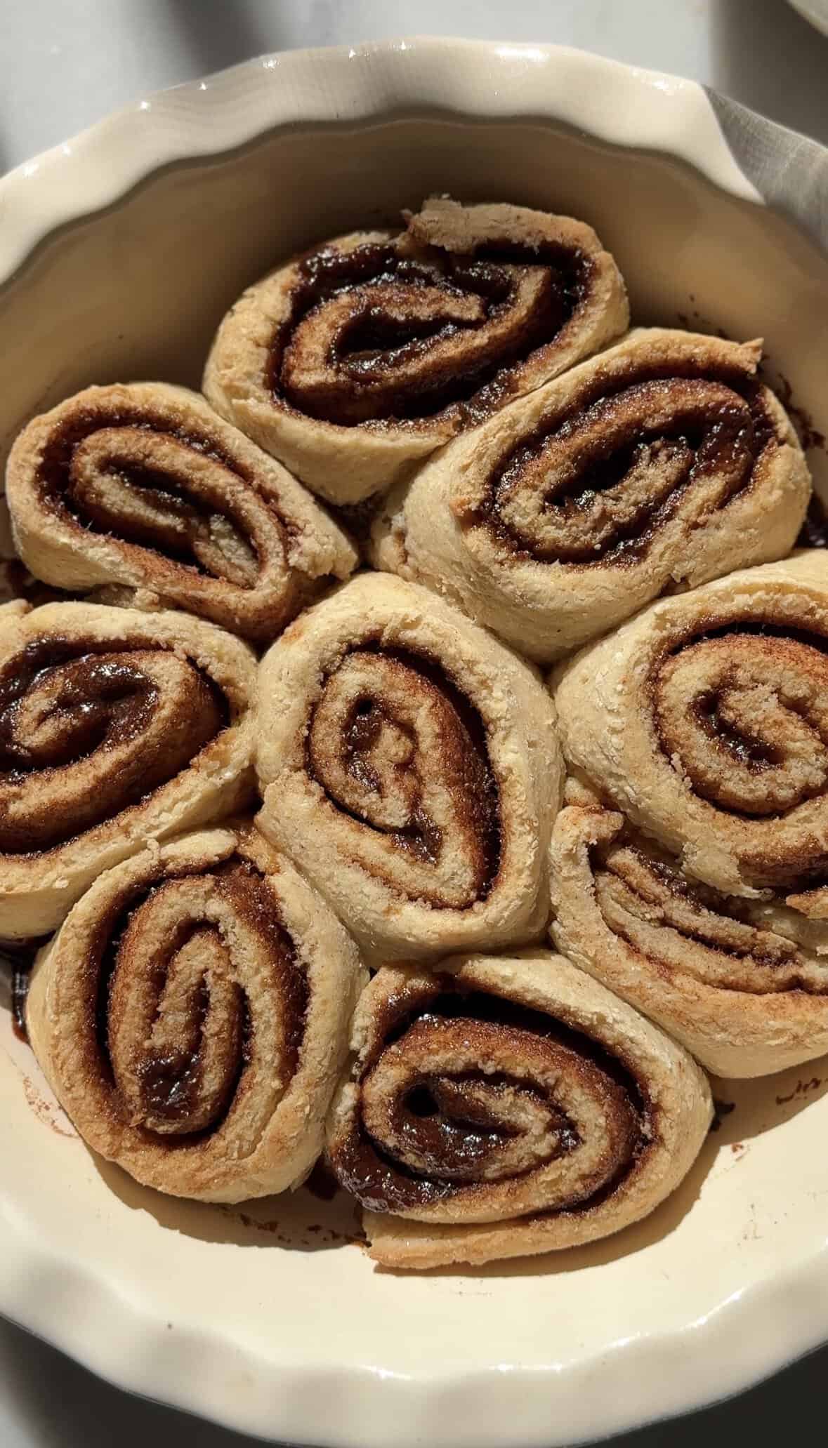 Eight gluten-free cinnamon rolls baked in a baking dish.