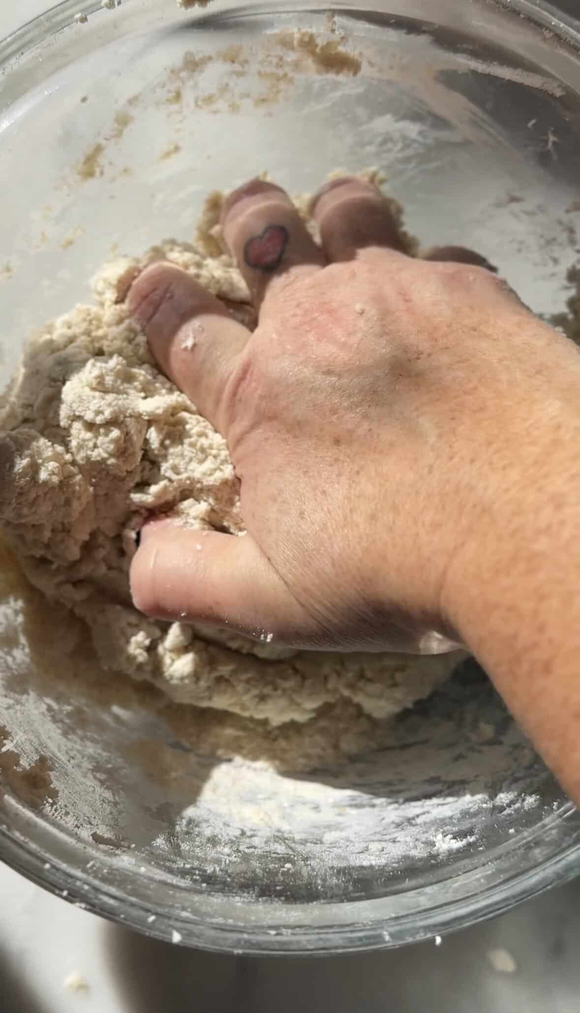 Mix the dry and wet ingredients of the gluten-free cinnamon roll dough in the bowl with hand.